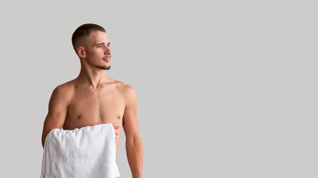 Front view of shirtless man holding towel with copy space
