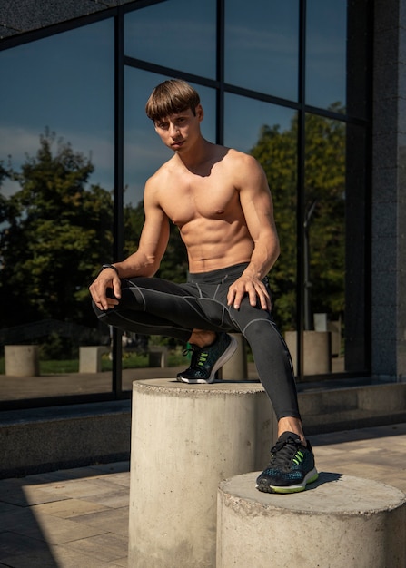 Front view of shirtless man posing outdoors while working out
