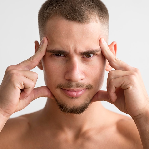 Front view of shirtless man posing with fingers to his temples
