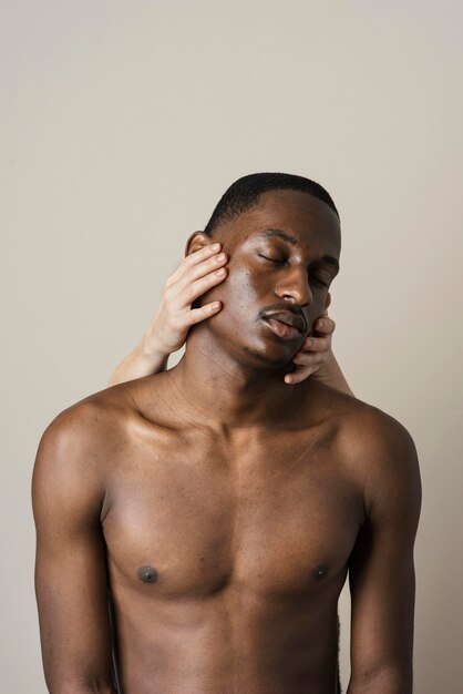 Front view of shirtless man posing with hands on his face