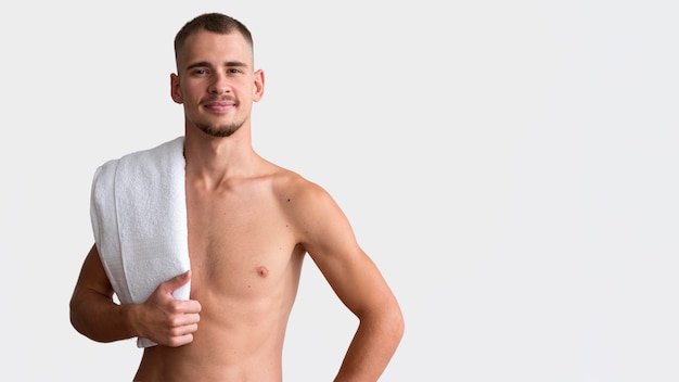 Front view of shirtless man posing with towel and copy space