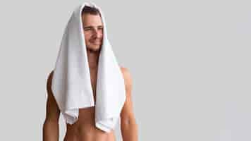 Free photo front view of shirtless man posing with towel over his head