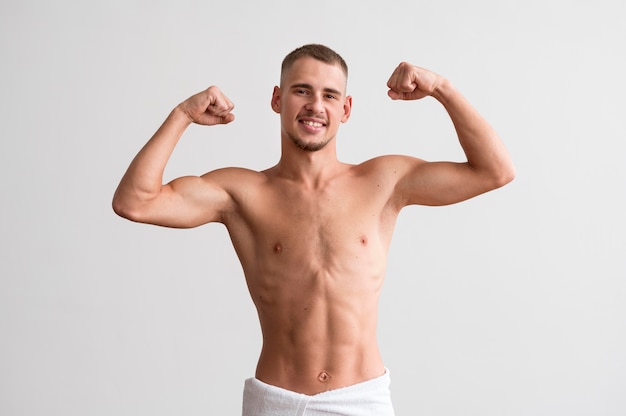 Front view of shirtless man showing off his biceps