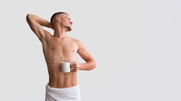 Front view of shirtless man stretching in the morning with copy space