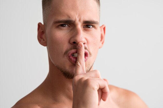 Front view of shirtless man telling you to be quiet