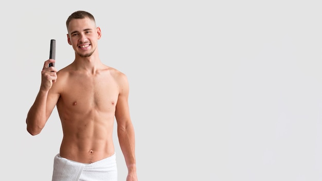 Front view of shirtless man in a towel holding comb