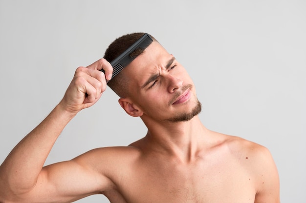 Front view of shirtless man using a comb