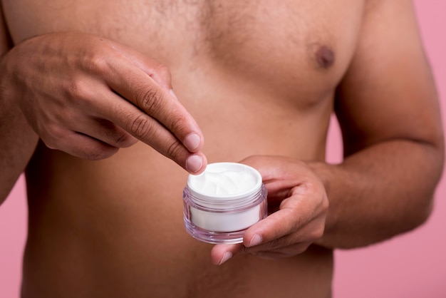 Front view of shirtless man using face cream