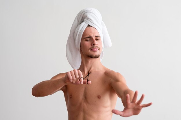 Free photo front view of shirtless man with towel on his head looking at his fingernails