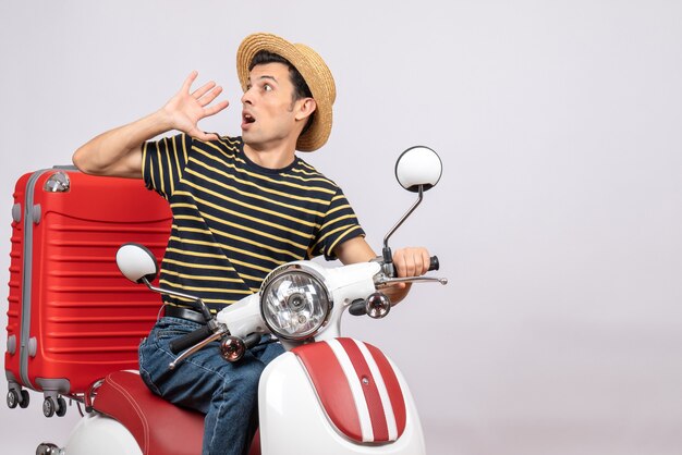 Front view of shocked young man with straw hat on moped