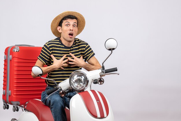 Front view of shocked young man with straw hat on moped