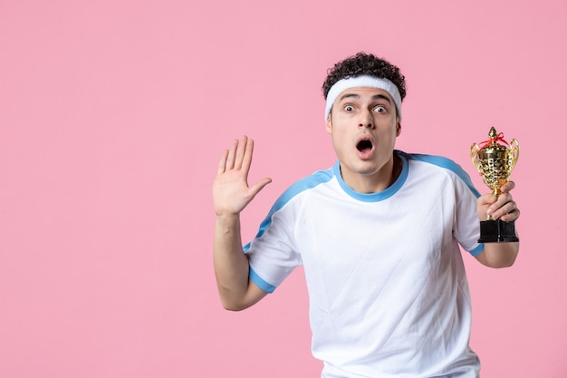 Front view shocked young player in sport clothes with golden cup