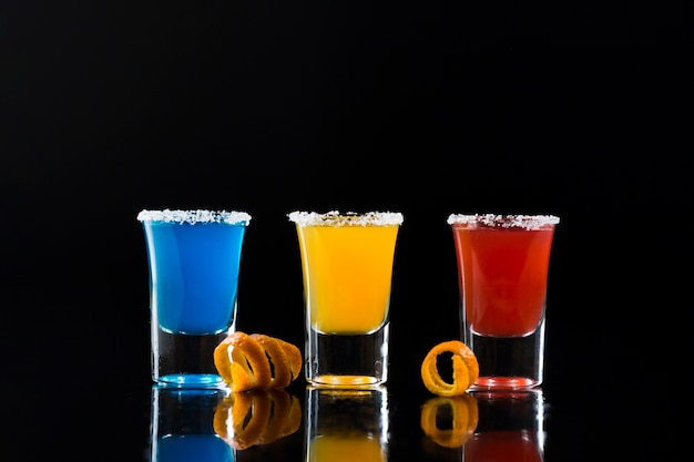Вид спереди рюмки с красочными коктейлями