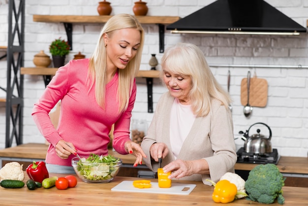 Front view shot of mother and daughter cutting a sweet pepper