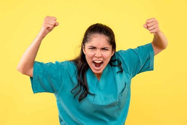 Front view shouting female doctor in uniform standing on yellow isolated background