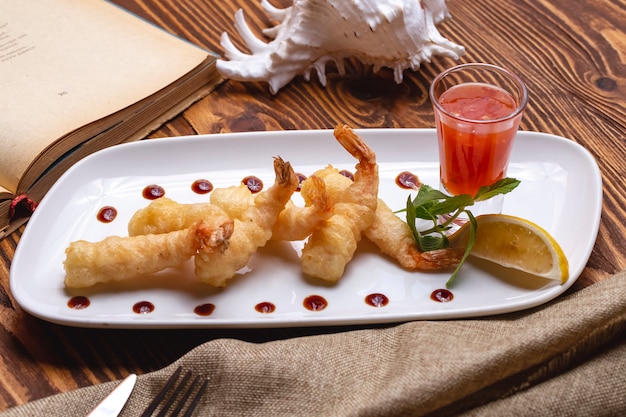 Front view shrimp in batter with sauce and a slice of lemon