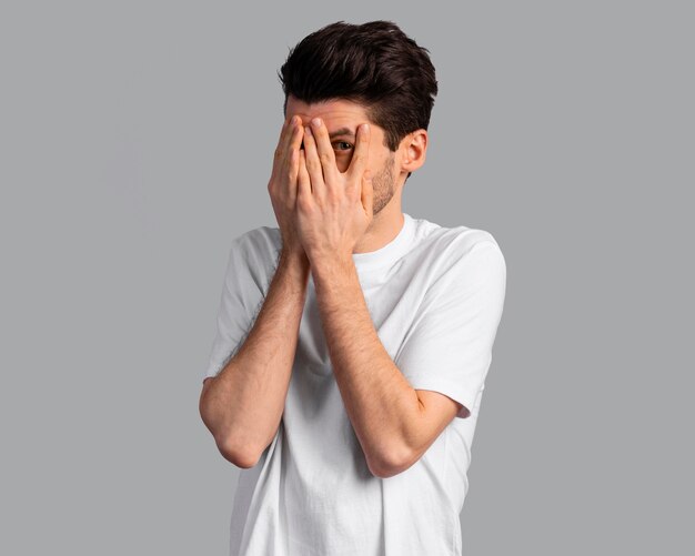 Front view of shy man covering his eyes with his hands