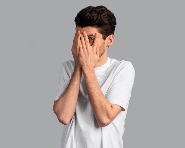 Front view of shy man covering his eyes with his hands