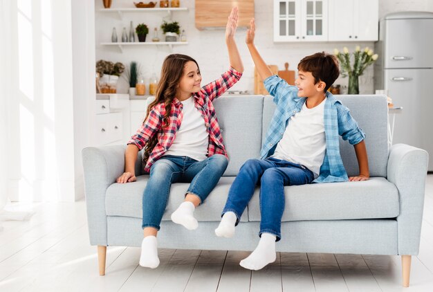 Front view siblings on couch high five