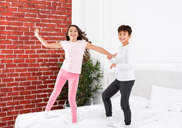 Front view siblings jumping in bed