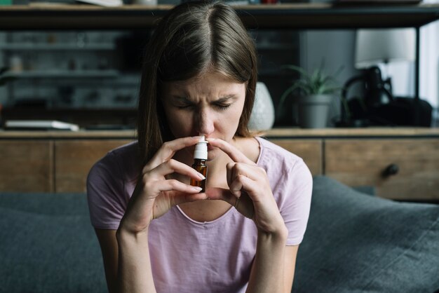 Front view of a sick woman sniffing nasal spray