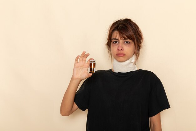 Вид спереди больная молодая женщина чувствует себя плохо и держит таблетки на белой поверхности