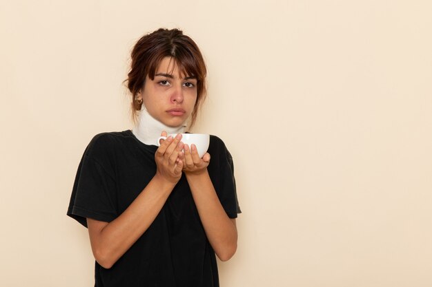 Front view sick young female feeling very ill and drinking herb tea on a white surface