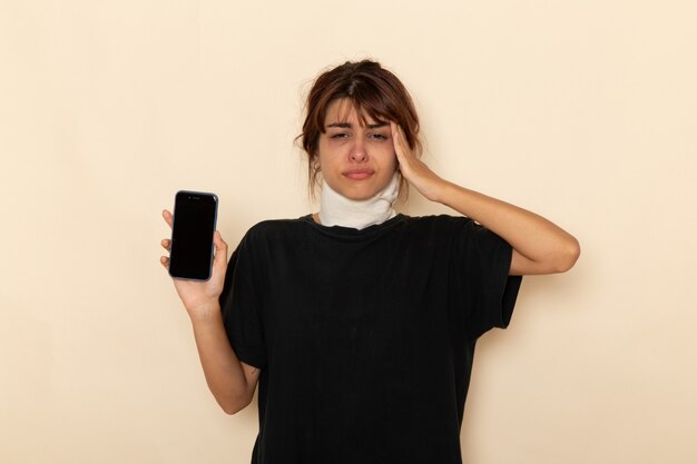 Front view sick young female feeling very ill and holding phone having headache on white surface