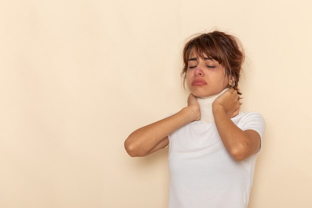Вид спереди больной молодой женщины с высокой температурой, покрывающей ее горло, чувствуя себя плохо на белой поверхности
