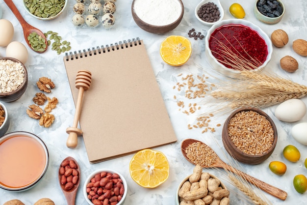 Front view simple notepad with eggs flour jelly different nuts and seeds on white background nut color cake sweet pie photo sugar dough fruit