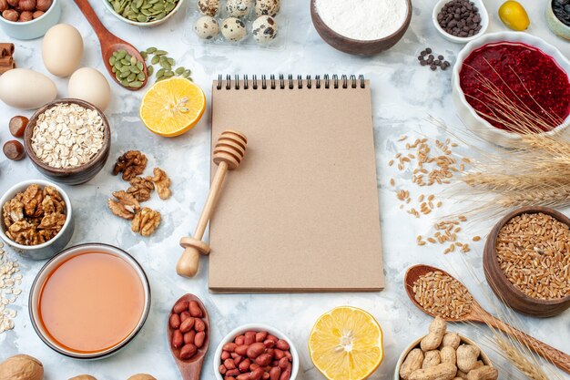 Front view simple notepad with eggs flour jelly and different nuts on white background nut color cake sweet pie photo sugar dough fruit