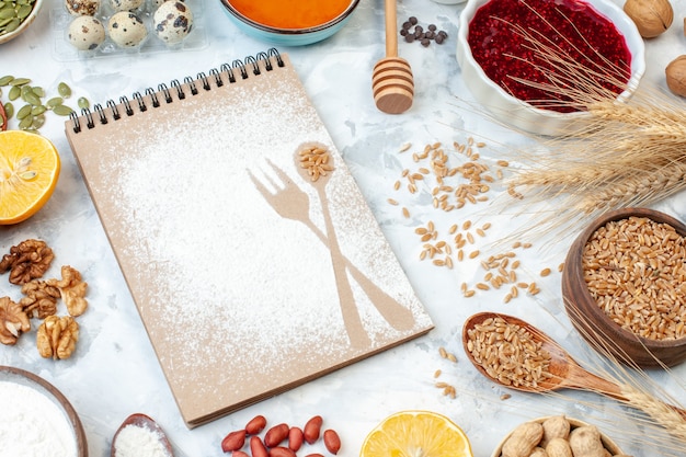 Free photo front view simple notepad with flour eggs jelly and different nuts on a white background fruit nut sugar color pie photo sweet cake dough