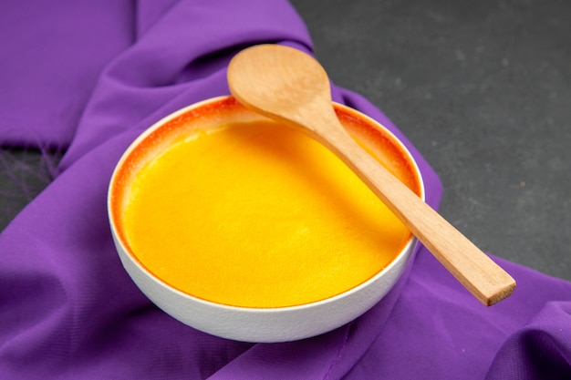 Front view simple pumpkin soup on purple tissue