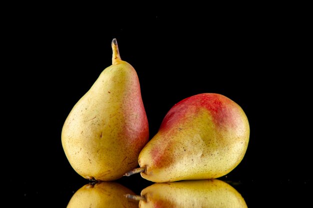 Front view of single whole ripe yellow with red pears lying on black background with free space