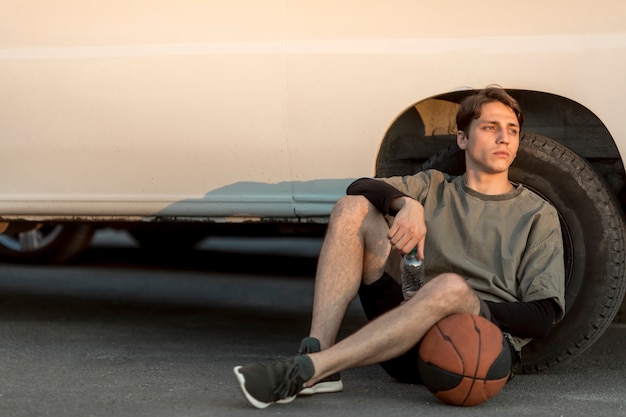 Free photo front view sitting man with a basketball