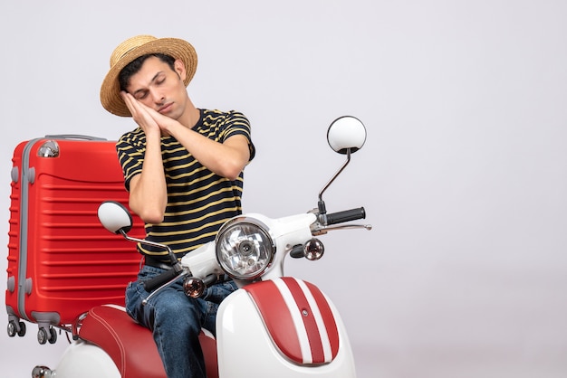 Front view of sleeping young man with straw hat on moped