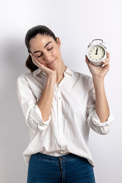 Front view of sleepy woman holding clock