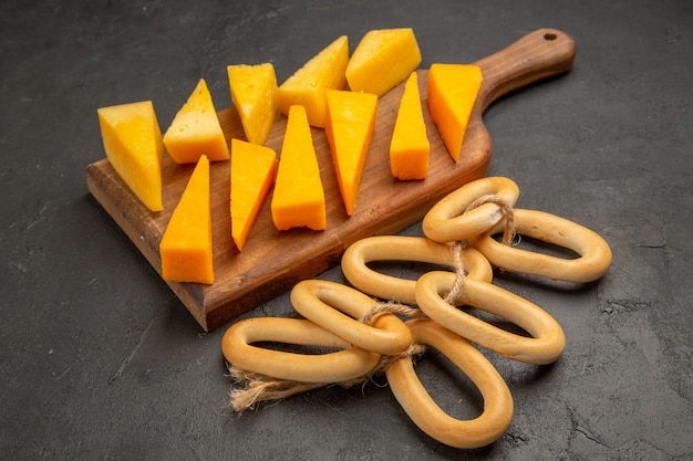 Вид спереди нарезанный свежий сыр со сладкими крекерами на темной закуске цветная фотография завтрака