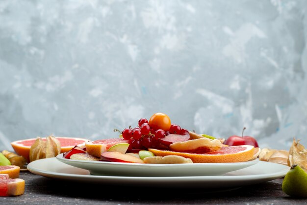 木製デスクフルーツ色食品柑橘類の白いプレート内の熟した新鮮な果物をスライスした正面図