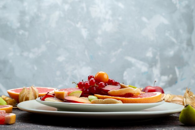 A front view sliced fresh fruits ripe and mellow inside white plate on the wooden desk fruit color food citrus