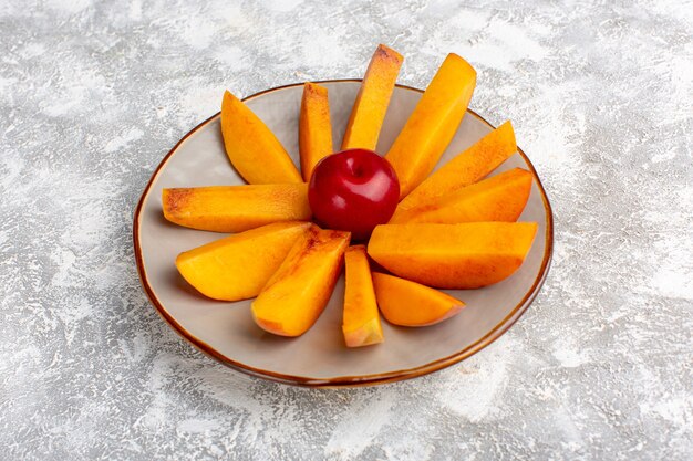 Front view sliced fresh peaches inside plate on the light-white background.