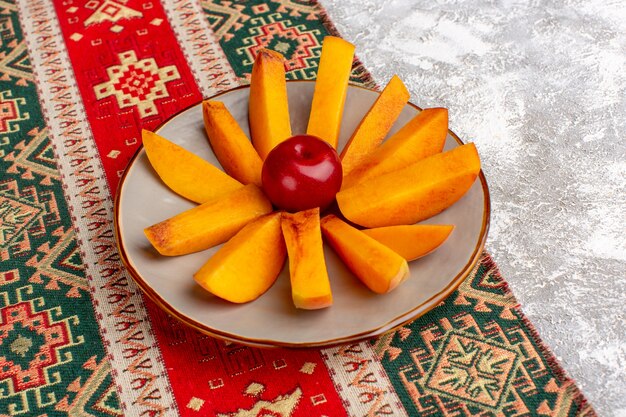 Вид спереди нарезанные свежие персики внутри тарелки на белом фоне.