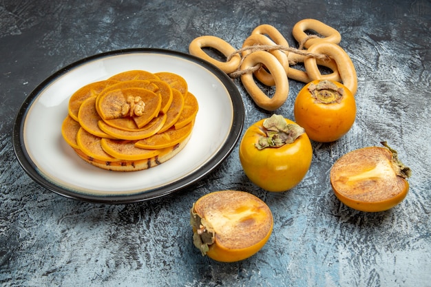 Free photo front view of sliced persimmon with pancake on a light surface