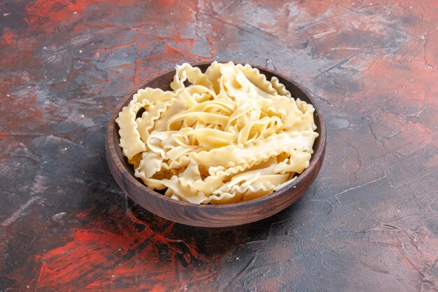 Вид спереди нарезанное сырое тесто внутри тарелки на темной поверхности тесто макароны сырая темная еда