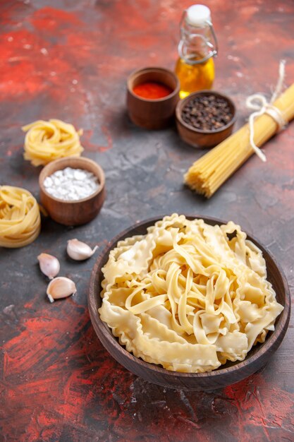 Front view sliced raw dough with seasonings on a dark surface pasta dough dark food