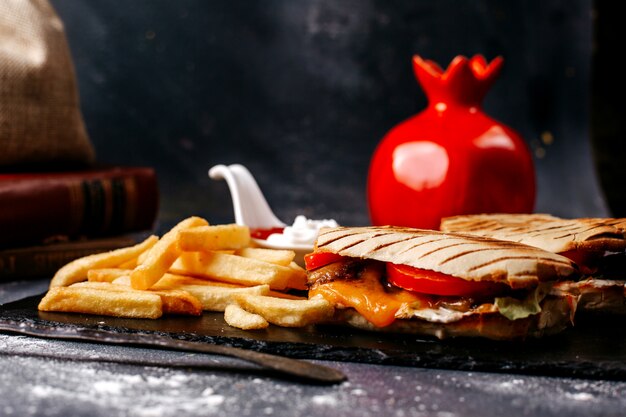 Front view sliced sandwich along with french fries on the grey floor