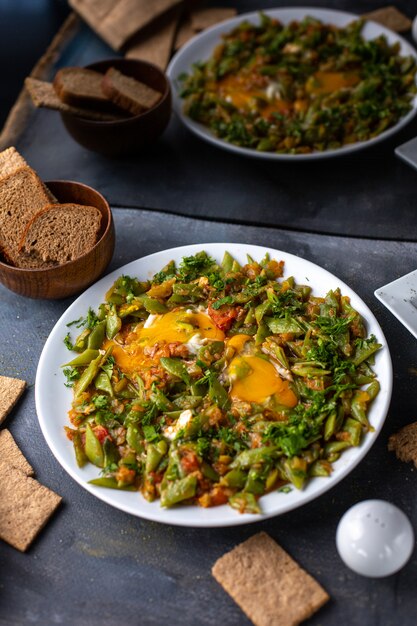 A front view sliced vegetable meal colorful tasty inside white plate along with crisps eggs on the grey table dish vegetables