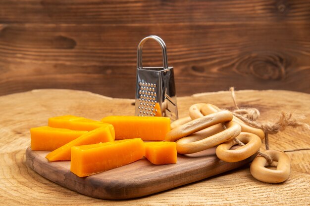 Front view slices of cheese box grater oval bagels on cutting board on wooden ground