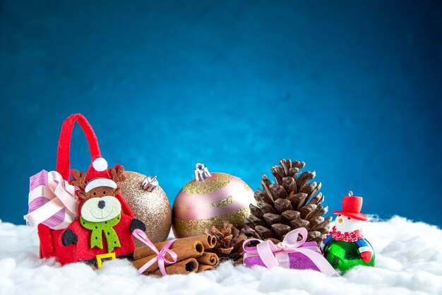 전면보기 작은 사슴 가방 계피 스틱 크리스마스 장식품 파란색 절연 표면에 pinecone