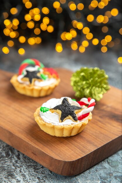 Front view small tarts on serving board xmas ornaments on dark isolated surface